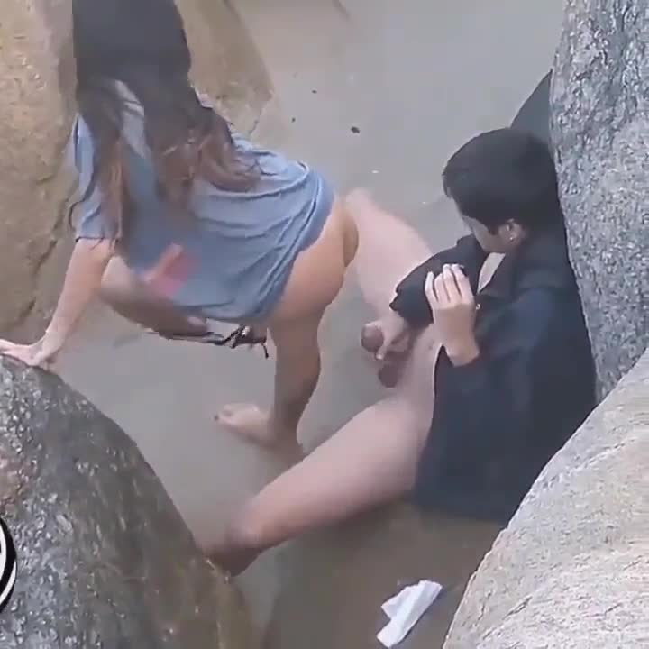 Un couple surpris en train de baiser derrière les rochers